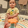 baby, child, infant, playpen, toy, colorful_bedding, yellow_shirt, smiling_lemon_graphic, feet, hands, mesh_sides, quilt, soft_toy, indoor, cute, portrait, sitting, looking_at_camera, young_child, play_area