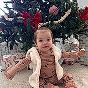 Maríaelisa is registered to the contest to win money with this photo: baby, child, christmas_tree, holiday, presents, gift_wrap, red_bow, carpet, indoor, festive, decorations, vest, pajamas, socks, cute, smiling, sitting, toy, holiday_season, home
