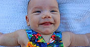 Briar joined the competition — help win amazing prizes! baby, infant, smile, happy, toddler, face, clothing, colorful, pattern, button, arm, blanket, texture, skin, portrait, cute, lying_down, closeup, person, outdoor