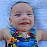 baby, infant, smile, happy, toddler, face, clothing, colorful, pattern, button, arm, blanket, texture, skin, portrait, cute, lying_down, closeup, person, outdoor