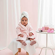 Victorina Gaitán is registered to the contest to win money with this photo: baby, child, towel, bathrobe, pink, white, stool, table, bath_salts, brush, sponges, indoors, portrait, cute, soft_lighting, skin_care, relaxation, toddler, face, sitting