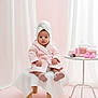 baby, bath_salts, bathrobe, brush, child, cute, face, indoors, pink, portrait, relaxation, sitting, skin_care, soft_lighting, sponges, stool, table, toddler, towel, white