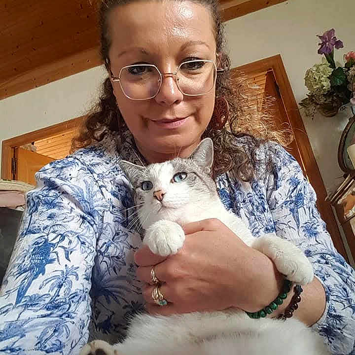 Neige a rejoint le concours — aidez-le/la à gagner de superbes lots ! blue_eyes, bracelets, cat, cozy, curly_hair, door, feline, flower, glasses, holding, indoor, patterned_clothing, pet, plant, portrait, rings, shirt, smile, woman, wooden_ceiling