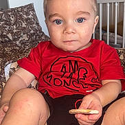 Lyham participe au concours pour gagner de l'argent avec cette photo : child, toddler, baby, kid, face, eyes, blue_eyes, blond_hair, hair, red_shirt, shirt, cookie, snack, crib, bedding, pillow, blanket, sitting, portrait, indoor