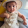 baby, infant, hat, romper, clothing, face, eyes, skin, hand, cute, portrait, indoors, soft_light, expression, child, young, sitting, button, headwear, person