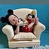baby, infant, mickey_mouse, costume, armchair, plush_toy, sign, blue_background, cute, red_clothing, black_clothing, smiling, small_chair, soft_rug, child, portrait, sitting, indoor, newborn, toy