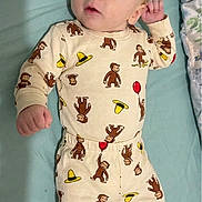 Wyatt is registered to the contest to win money with this photo: baby, infant, pajamas, monkey_pattern, bed, bedding, blanket, sleepwear, child, cute, lying_down, hand, foot, expression, person, indoors, soft_light, casual, resting, awake