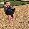 baby, child, swing, playground, park, grass, wood_chips, smile, happy, overalls, denim, barefoot, outdoor, daylight, picnic_table, swing_set, person, infant, joyful, fun