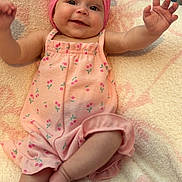 Esme is registered to the contest to win money with this photo: baby, child, infant, smiling, happy, portrait, pink_bow, headband, romper, floral_clothing, lying_down, raised_arms, outstretched_hand, barefoot, blanket, cozy, indoor, carpet, close_up, candid