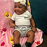 Miangel is registered to the contest to win money with this photo: baby, child, smiling, headband, white_clothing, shorts, sneakers, blanket, cartoon, pink, sharks, happy, tongue_out, cute, infant, sitting, indoors, hand_bracelet, fabric, person