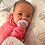 Lillianna is registered to the contest to win money with this photo: baby, pacifier, pink_clothing, blanket, patterned_blanket, infant, face, hand, lying_down, close_up, cute, soft_lighting, indoors, sleeping_area, child, newborn, head, expression, cozy, resting