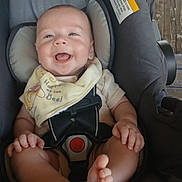 Espn is registered to the contest to win money with this photo: baby, car_seat, smiling, feet, bib, happy, child, infant, sitting, clothing, straps, wooden_floor, cute, young_child, person, indoor, seat, protection, secure, joyful