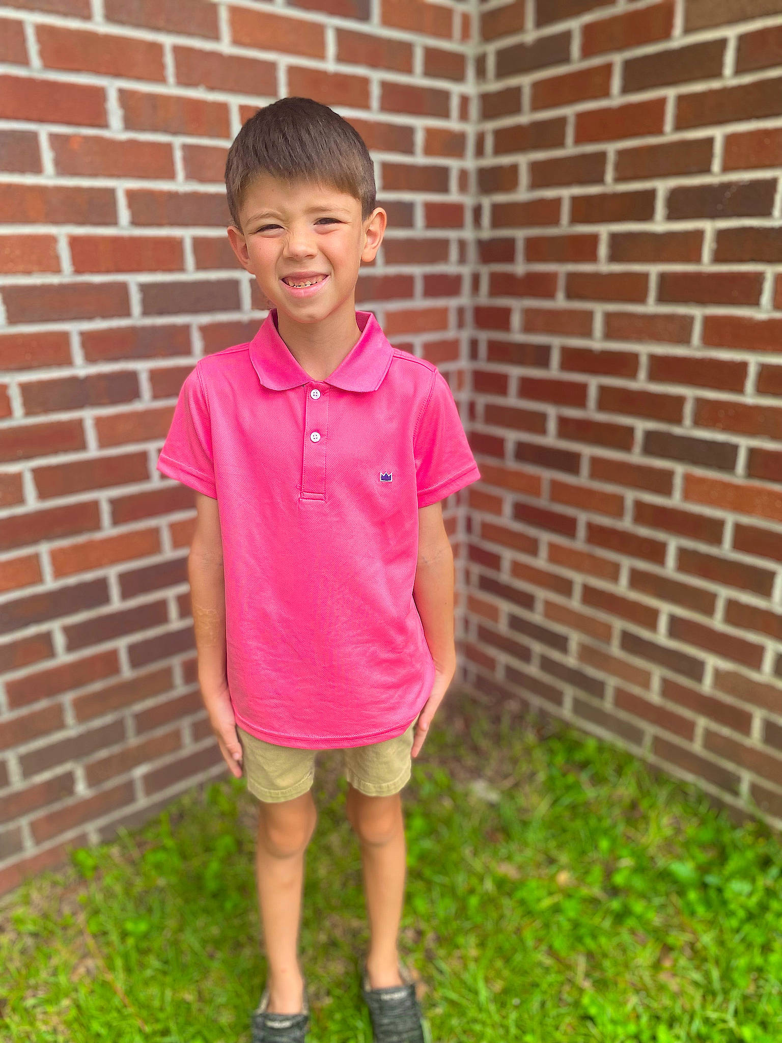 Conner is registered to the contest to win money with this photo: brick, brickwork, child, chin, clothing, fun, grass, happy, joy, leisure, magenta, person, sandal, shorts, sleeve, smile, t_shirt, toddler, vacation