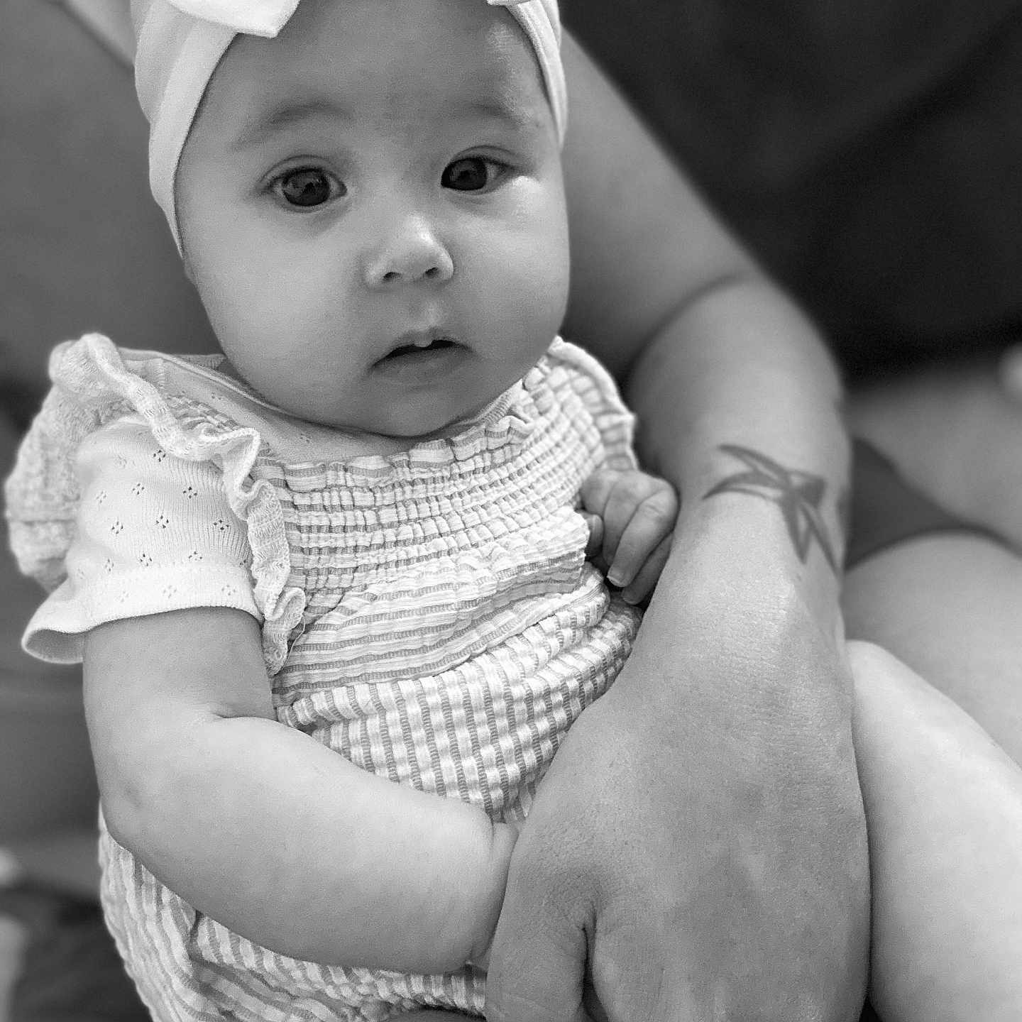 Elyn participe au concours pour gagner de l'argent avec cette photo : arm, baby, black_and_white, bow, child, closeup, clothing, cute, expression, fashion, hand, headband, holding, infant, person, portrait, ruffles, skin, tattoo, young