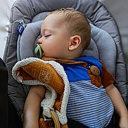 Olanto participe au concours pour gagner de l'argent avec cette photo : baby, sleeping, car_seat, pacifier, blanket, child, infant, clothing, seatbelt, comfort, peaceful, rest, cute, soft_toy, head, face, arm, indoors, portrait, relaxation