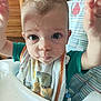 baby, child, messy_face, high_chair, bib, food, curly_hair, indoor, cute, expression, portrait, person, young_child, feeding_time, clothing, dining, kitchen, smudged_face, hands_up, close_up