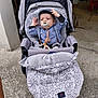 baby, stroller, pacifier, blanket, clothing, child, infant, person, outdoor, curious, cute, hat, comfort, seat, wheel, floor, gray, black, blue, expression