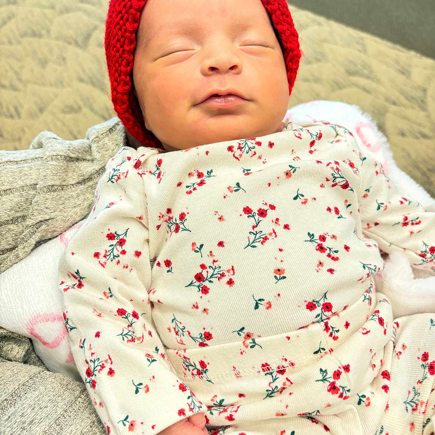 Yorgelis is registered to the contest to win money with this photo: baby, child, closeup, cozy, cute, fabric, floral_outfit, headwear, indoors, infant, knitted_headband, newborn, peaceful, portrait, red_headband, resting, sleeping, small, soft_blanket, tiny_hand