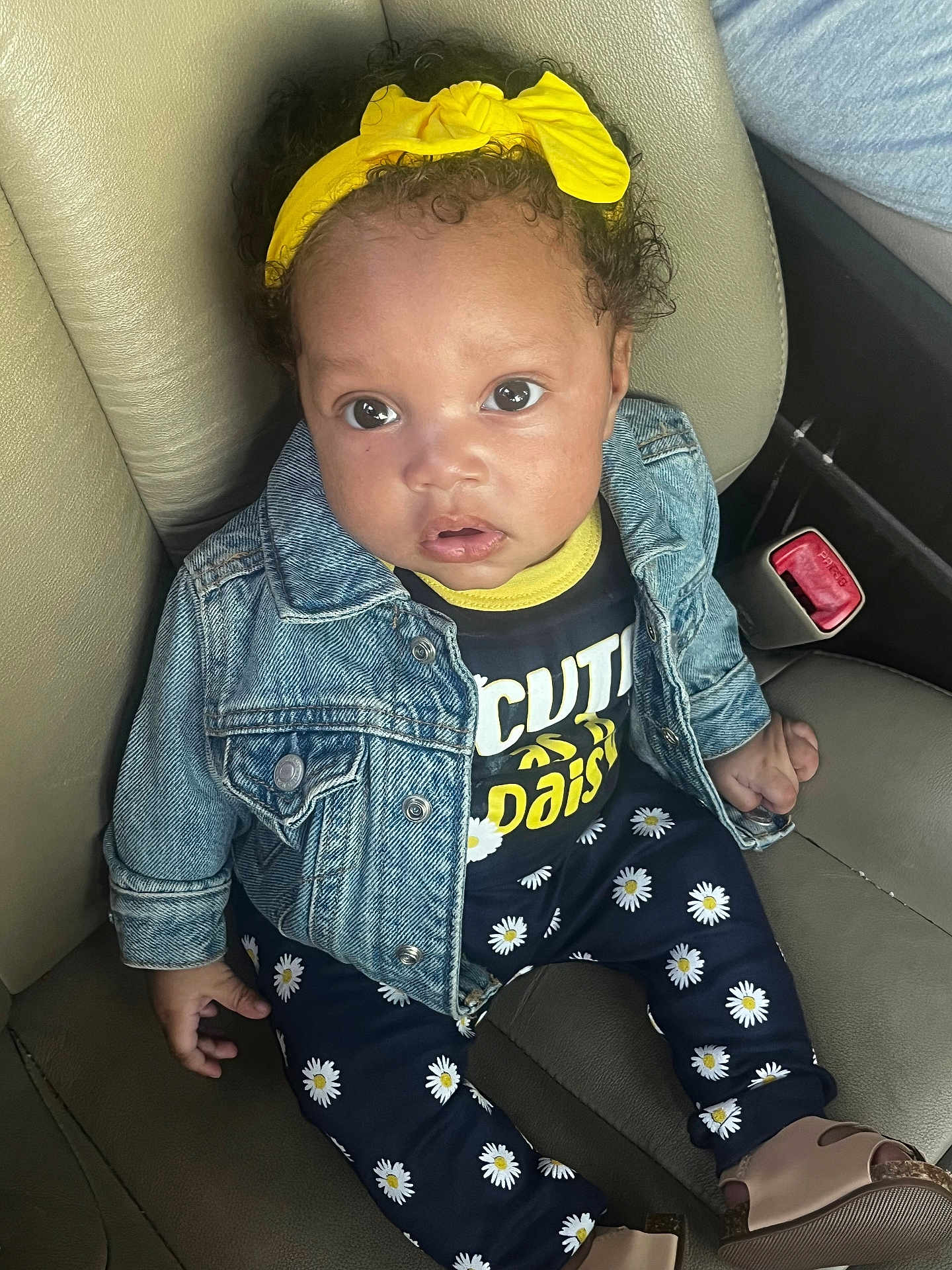 Jhournie is registered to the contest to win money with this photo: baby, child, denim_jacket, yellow_headband, daisy_pattern, pants, shoes, car_seat, leather, cute, curious, portrait, sitting, clothing, infant, face, eyes, hand, fashion, casual