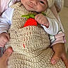 baby, crochet, hat, carrot, outfit, infant, hands, smile, cute, child, white_clothing, knitwear, person, portrait, seated, cozy, soft_toys, background, fabric, cute_expression