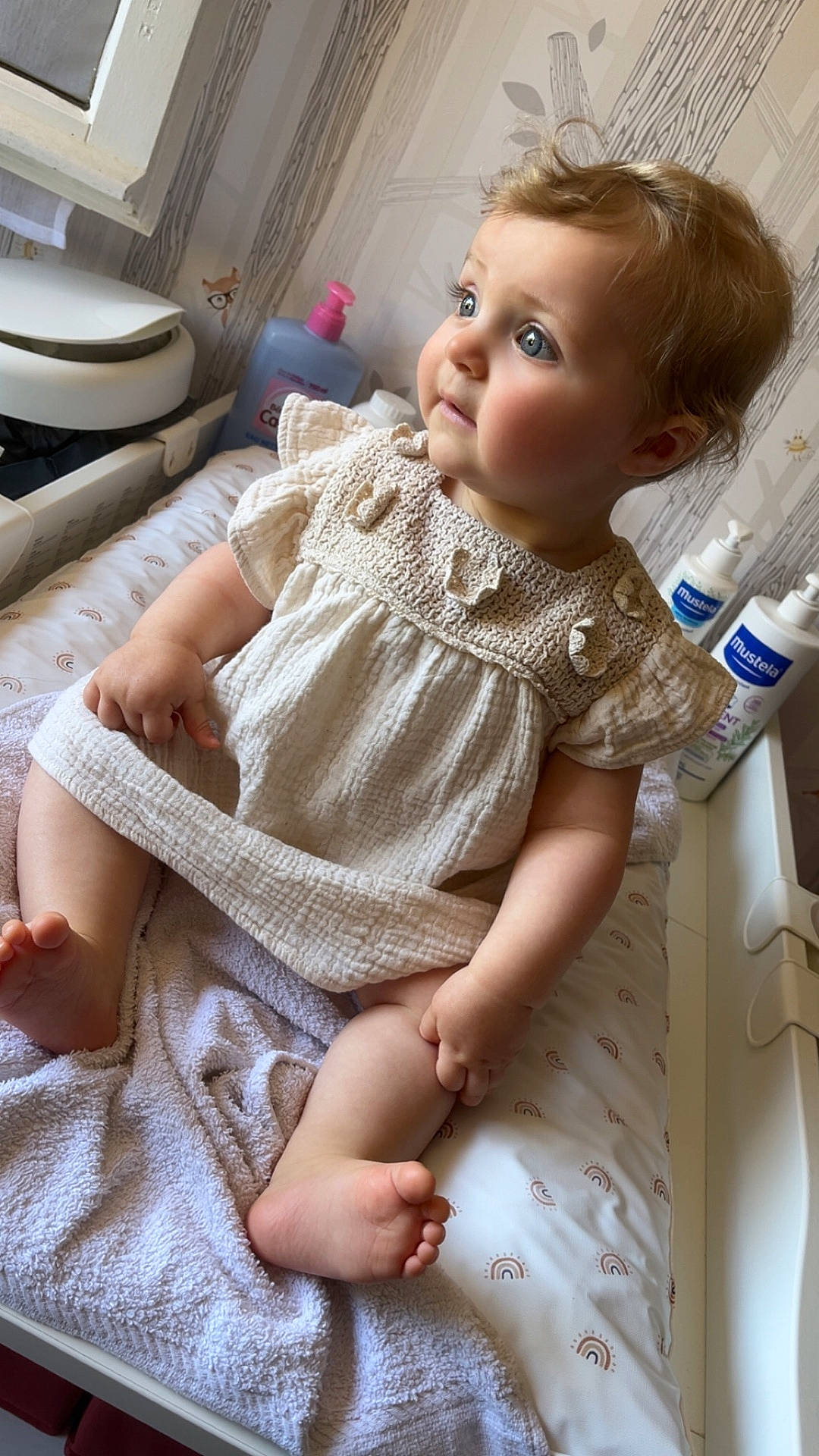 baby, baby_care, blanket, blue_eyes, changing_table, child, clothing, curly_hair, cute, expression, foot, hand, indoors, infant, lotion_bottles, portrait, room, sitting, skin, soft_light