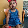 carpet, casual, chair, child, cute, denim_dress, furniture, happy, headband, indoor, patterned_chair, person, playful, portrait, red_bow, shoe, sitting, smiling, toddler, young_child