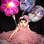 baby, child, pink_dress, headband, balloons, flower_balloon, birthday_balloon, celebration, portrait, cute, smiling, indoor, soft_blanket, feet, curly_hair, happy, festive, tulle, sitting, adorable