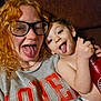 Michael is registered to the contest to win money with this photo: child, adult, glasses, tongue_out, couch, curly_hair, red_hair, water_bottle, diaper, shirt, indoor, portrait, closeup, playful, silly_face, family_moment, smile, upholstery, casual, relaxed