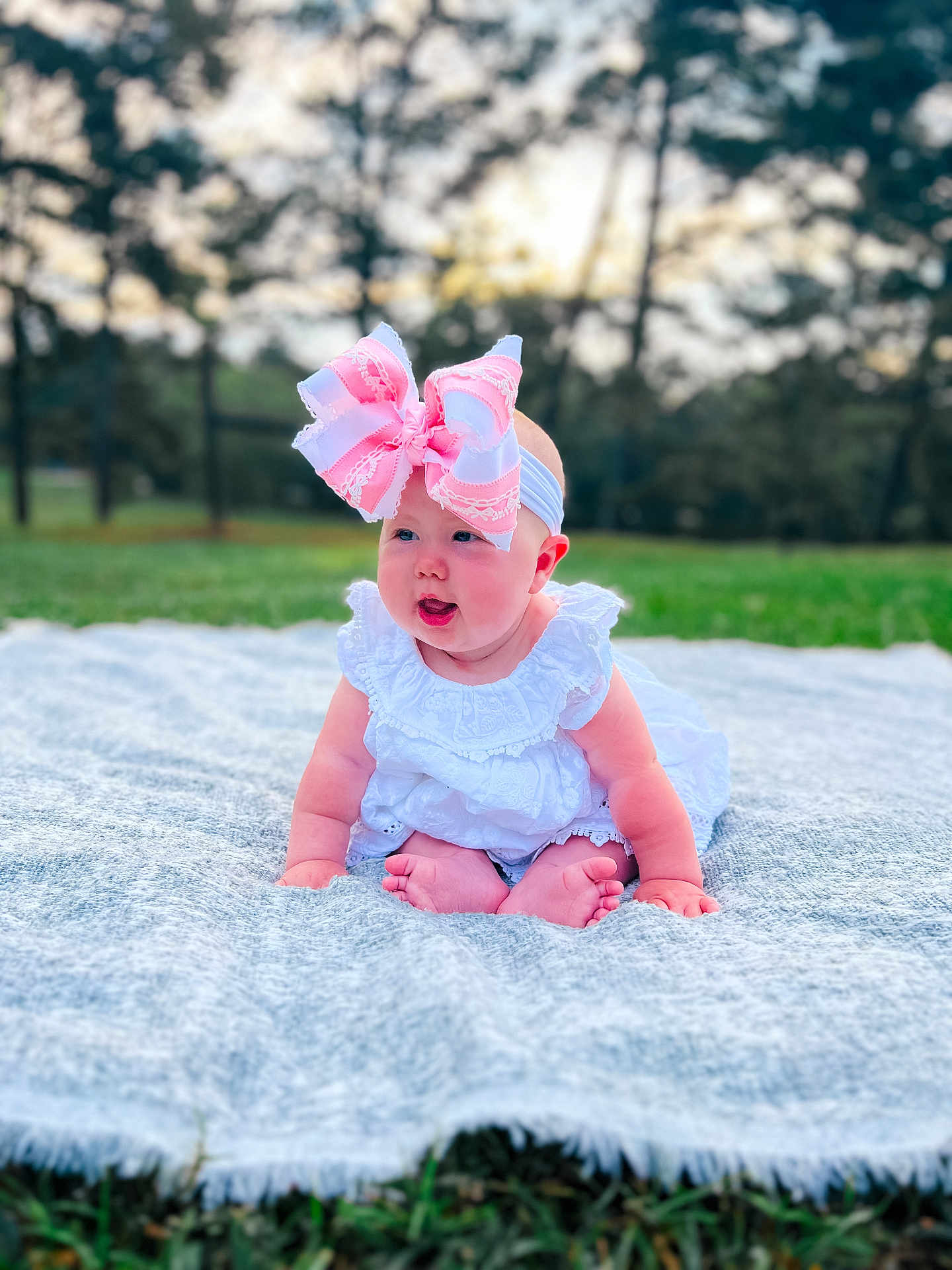 Emmy joined the competition — help win amazing prizes! baby, child, infant, bow, headband, white_dress, blanket, grass, outdoor, nature, cute, sitting, portrait, smiling, feet, hands, greenery, trees, daylight, soft_texture