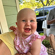Emmy is registered to the contest to win money with this photo: baby, child, smiling, happy, face, person, outdoor, daylight, dress, pink, floral, arm, hand, holding, adult, greenery, car, sitting, sleeveless, portrait