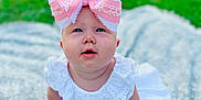 Emmy is registered to the contest to win money with this photo: baby, blanket, bow, candid, child, curious, cute, daylight, face, grass, greenery, hands, headwear, infant, outdoor, portrait, sitting, skin, soft_light, white_dress