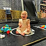 Emmy is registered to the contest to win money with this photo: baby, child, smiling, indoor, toys, treadmill, gym, fitness, mat, chalkboard, writing, floor, clothing, barefoot, exercise, equipment, chair, wood, brick, happy