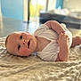 baby, infant, lying_down, blanket, white_clothing, indoors, curious, soft_light, face, hands, skin, head, expression, cozy, floor, background, child, cute, portrait, newborn