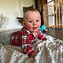 baby, child, infant, plaid_shirt, blanket, floor, blue_eyes, smiling, indoor, wooden_baby_gate, toy, red_clothing, cute, person, face, happy, home, crawling, soft_texture, young