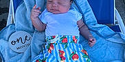 Leon is registered to the contest to win money with this photo: baby, infant, one_month, blue_chair, towel, colorful_shorts, white_socks, outdoor, sunlight, relaxing, cute, peaceful, hand_gesture, summer, child, portrait, clothing, skin, person, babywear