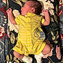 baby, newborn, sleeping, yellow_onesie, white_socks, floral_pillow, floral_blanket, infant, cute, peaceful, face_profile, hand, feet, fabric, pattern, cozy, indoors, resting, small_person, child