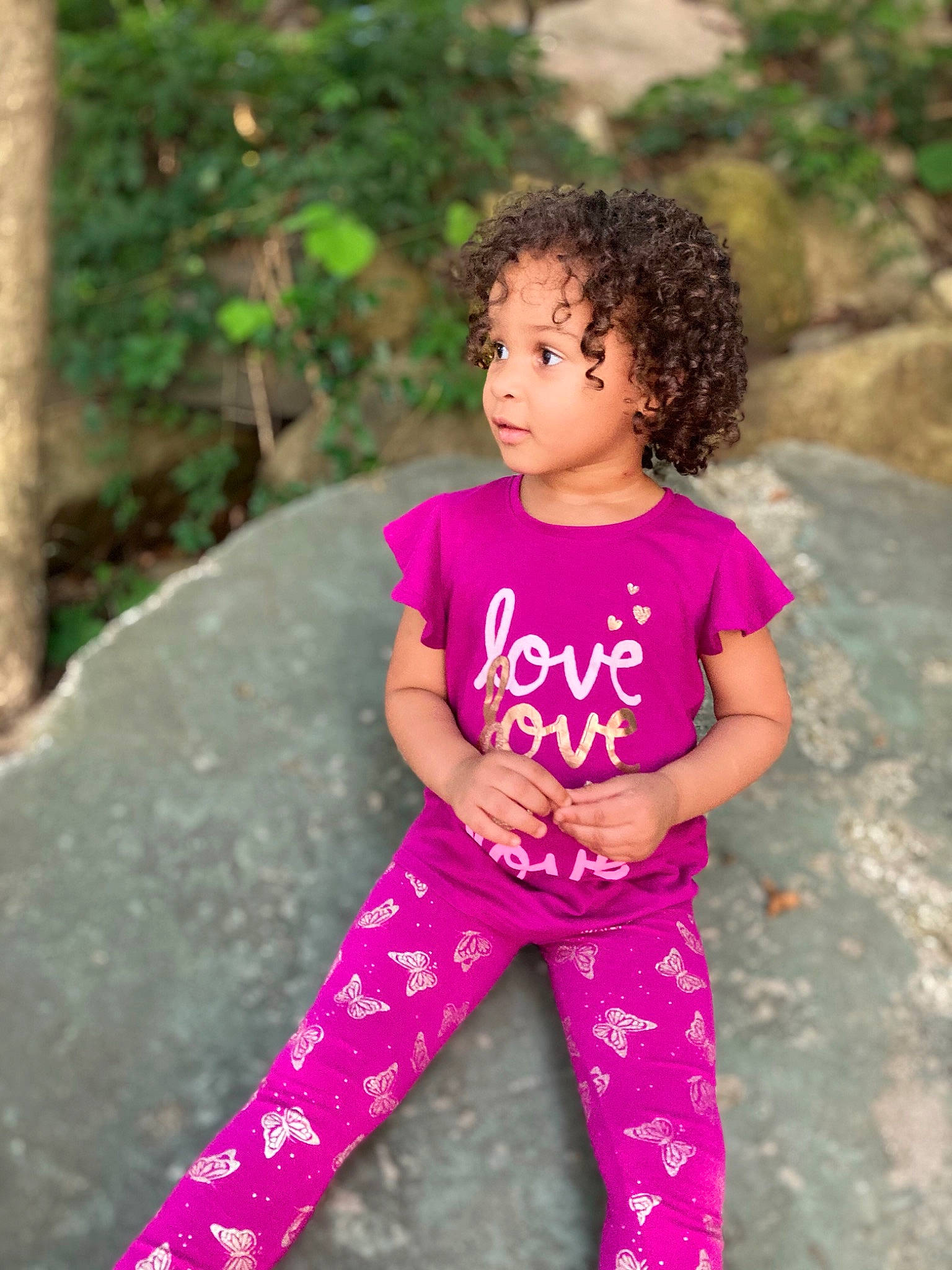 Amillia is registered to the contest to win money with this photo: baby_toddler_clothing, eye, facial_expression, grass, hair, hairstyle, happy, human_body, leisure, nature, people_in_nature, person, pink, plant, purple, shoulder, skin, sleeve, toddler, waist