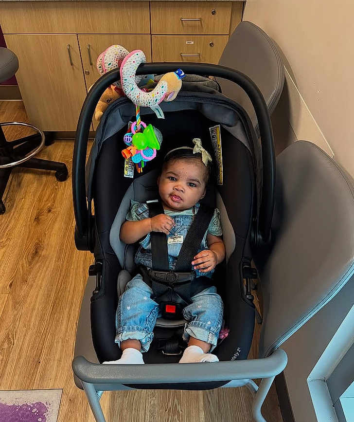 Island joined the competition — help win amazing prizes! baby, child, car_seat, denim_overalls, headband, toy, indoor, wooden_floor, chair, cabinet, flooring, baby_clothes, seat_belt, infant, cute, child_seat, room, baby_toy, sitting, calm