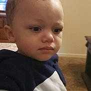 Stetson is registered to the contest to win money with this photo: toddler, child, indoor, curly_hair, hoodie, person, face, expression, young, carpet, furniture, brown_hair, closeup, portrait, casual_clothing, home, young_child, serious, curly_topknot, skin