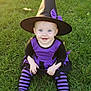 baby, child, witch_costume, hat, purple, black, striped_tights, grass, outdoor, smile, blue_eyes, sunlight, costume, sitting, cute, happy, playful, portrait, holiday, festive