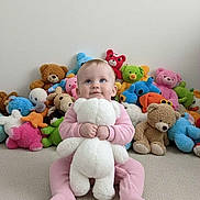 Miranda joined the competition — help win amazing prizes! baby, teddy_bear, stuffed_animals, pink_pajamas, carpet, child, toy, plush, smiling, sitting, indoor, cute, soft_toy, happy, floor, blue_eyes, infant, childhood, playtime, colorful