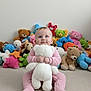 baby, teddy_bear, stuffed_animals, pink_pajamas, carpet, child, toy, plush, smiling, sitting, indoor, cute, soft_toy, happy, floor, blue_eyes, infant, childhood, playtime, colorful