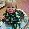 toddler, baby_walker, toy, child, smile, blonde_hair, indoor, wooden_floor, clothing, green_sweater, face, person, seat, playtime, infant, cute, happy, young_child, home, floor
