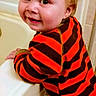 toddler, child, bathtub, bathroom, red_hair, striped_clothing, orange, brown, smile, face, person, young_child, cute, indoor, leaning, happy, clothing, hand, head, wall