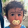 toddler, child, pacifier, curly_hair, blue_shirt, indoor, plant, window, face, portrait, young_child, expression, looking_up, person, cute, hair, innocence, baby, childhood, curly