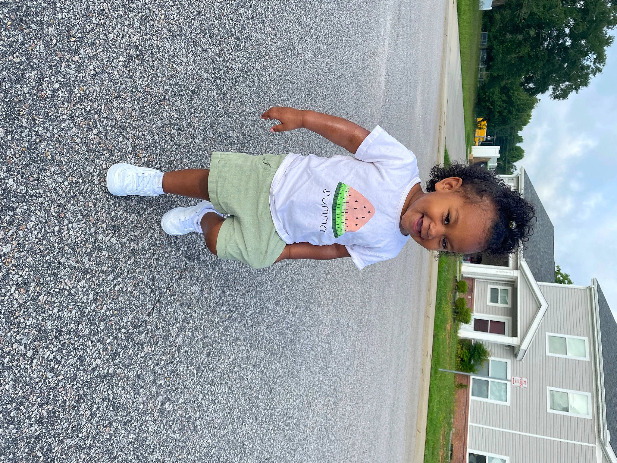 Reina is registered to the contest to win money with this photo: asphalt, building, child, cloud, fun, house, human_leg, joy, leisure, person, plant, recreation, road_surface, sidewalk, sky, t_shirt, tar, toddler, tree, walking_shoe