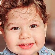 Idriss a rejoint le concours — aidez-le/la à gagner de superbes lots ! toddler, child, smiling, face, curly_hair, brown_eyes, bib, mickey_mouse, clothing, portrait, cute, happy, indoors, baby, infant, closeup, person, young_child, expression, soft_background