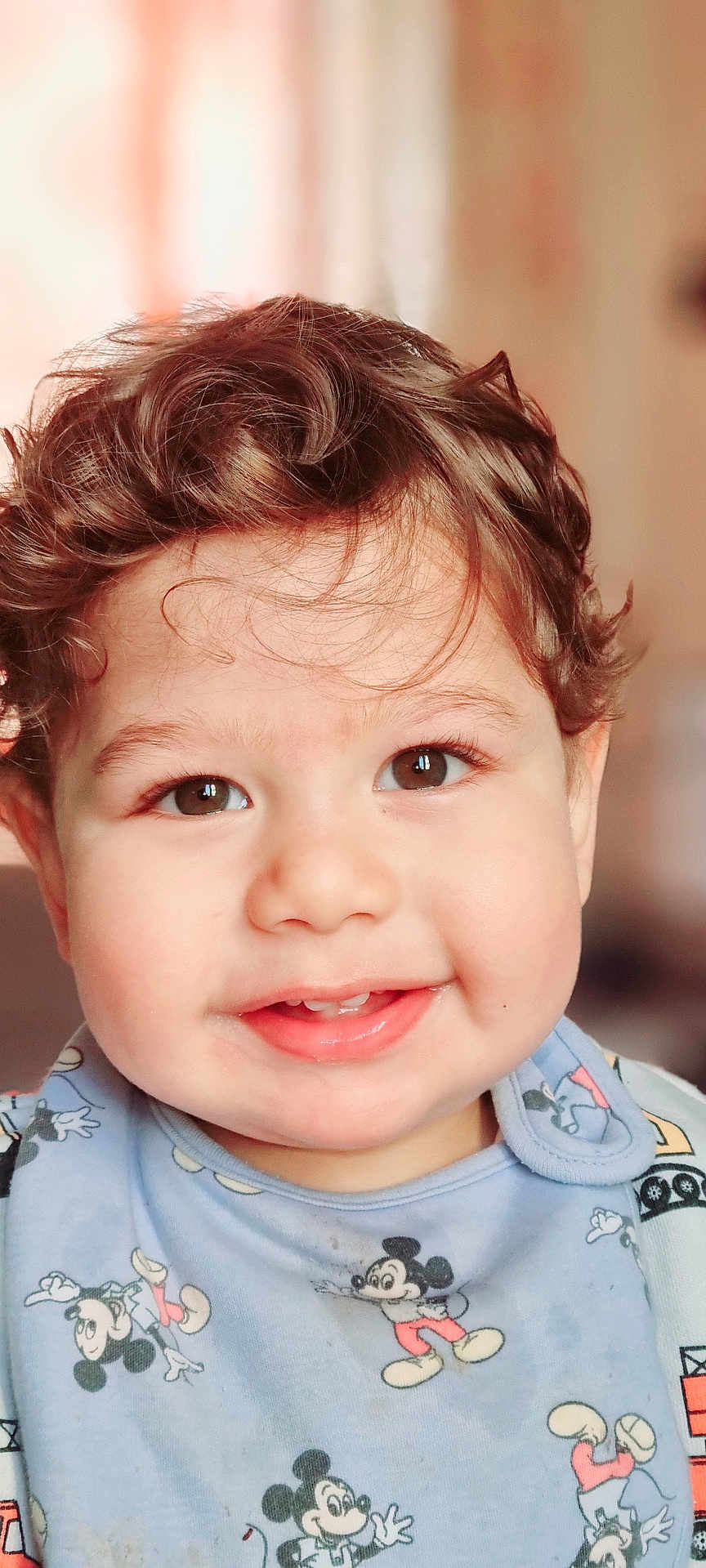 Idriss a rejoint le concours — aidez-le/la à gagner de superbes lots ! toddler, child, smiling, face, curly_hair, brown_eyes, bib, mickey_mouse, clothing, portrait, cute, happy, indoors, baby, infant, closeup, person, young_child, expression, soft_background