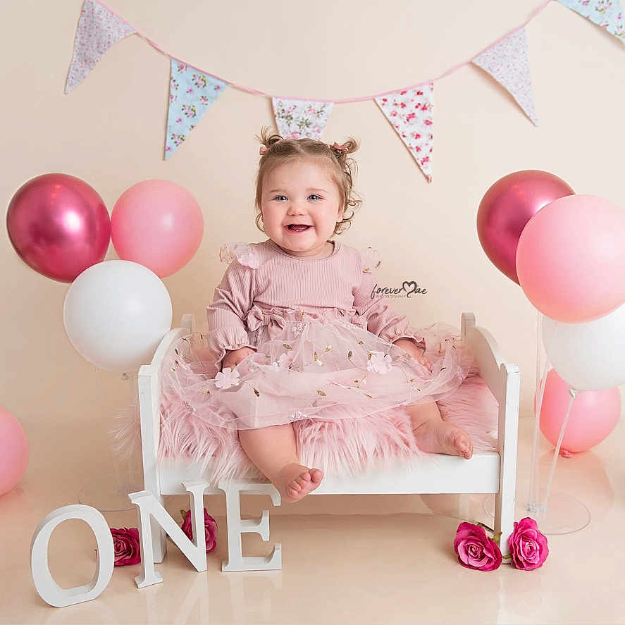 Olivia is registered to the contest to win money with this photo: baby, balloons, bed, birthday, blanket, celebration, child, cute, decorations, flag_bunting, flowers, happy, infant, one_year_old, photography, pink, pink_dress, portrait, smile, studio