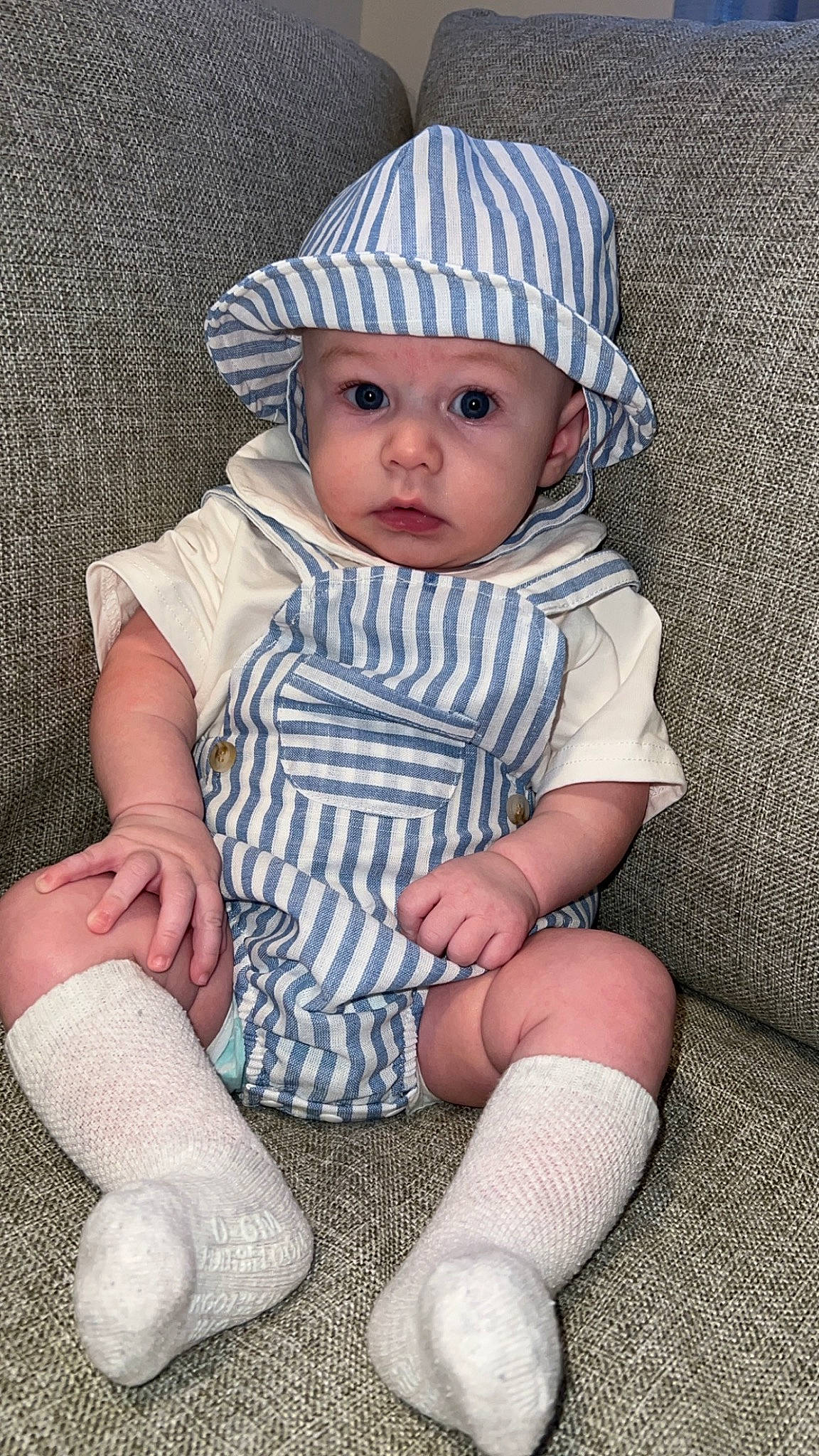 Zayden is registered to the contest to win money with this photo: baby, baby_toddler_clothing, beanie, cap, child, collar, face, fashion_accessory, grass, headwear, human_leg, knit_cap, pattern, person, portrait_photography, sitting, skin, sleeve, sock, sun_hat